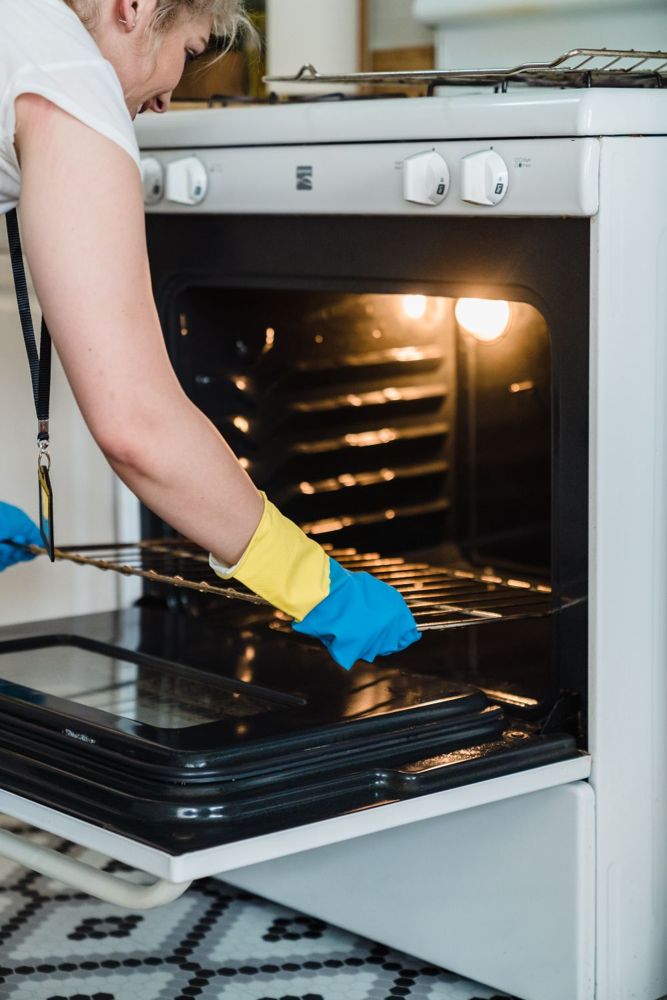 Person in gloves cleaning inside an oven during a deep clean