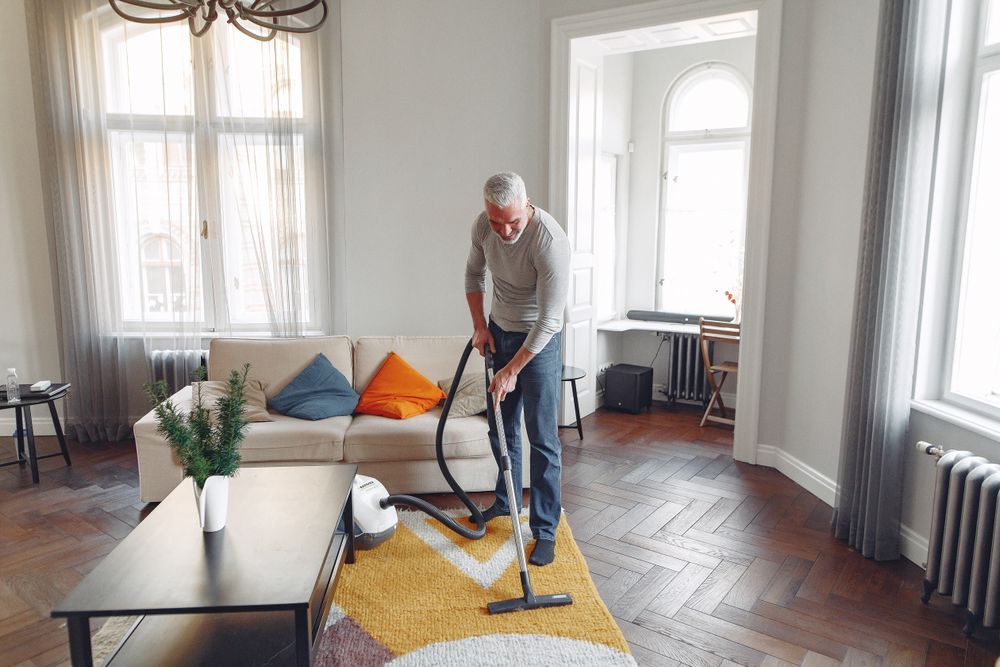 Person vacuuming a living room carpet during a deep clean